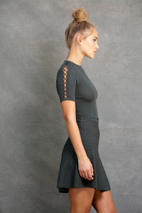 Alexa Fit and Flare Dress - VIAVAI FASHION  CLOSE UP  Profile view of a BLOND model with her hair up in a messy bun, wearing a fit andf flare knit dress in OLIVE color with beautiful textures and open knit details 