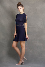 Alexa Fit and Flare Dress - VIAVAI FASHION  Profile view of a brunette model in nude heels, with her hair up in a messy bun, wearing a fit andf flare knit dress in Navy color with beautiful textures and open knit details 