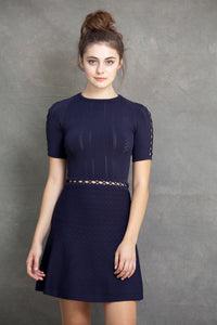 Alexa Fit and Flare Dress - VIAVAI FASHION  A brunette model with her hair up in a messy bun, wearing a fit andf flare knit dress in Navy color with a beautiful texture and open knit details 