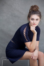 Alexa Fit and Flare Dress - VIAVAI FASHION  CLOSE UP Profile view of a brunette model with her hair up in a messy bun, wearing a fit andf flare knit dress in Navy color with beautiful textures and open knit details 